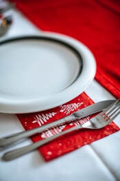 Picture of Christmas themed place setting, white plate and red napkin.